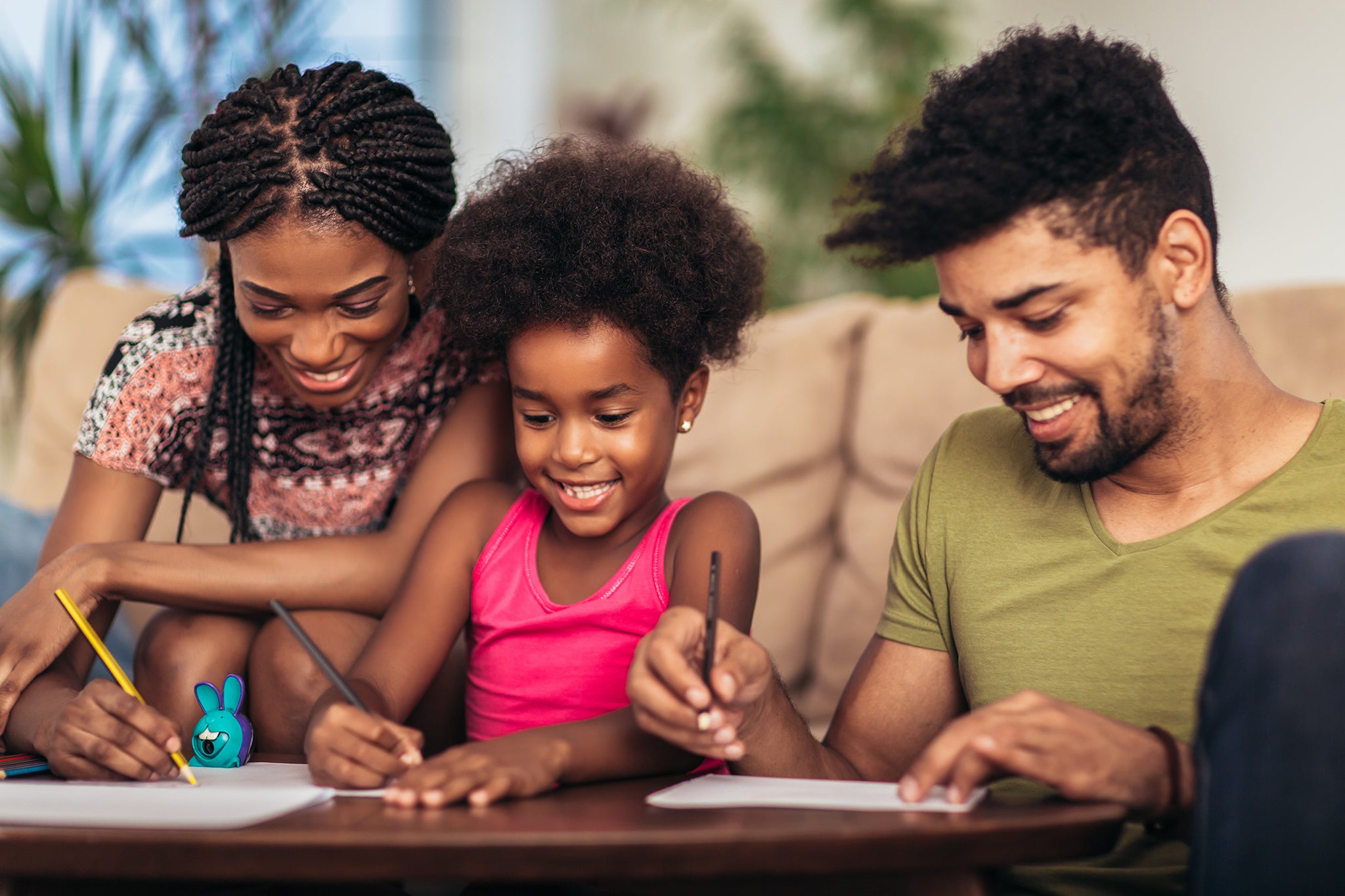 Woman, man and young girl sitting on the couch and drawing together
