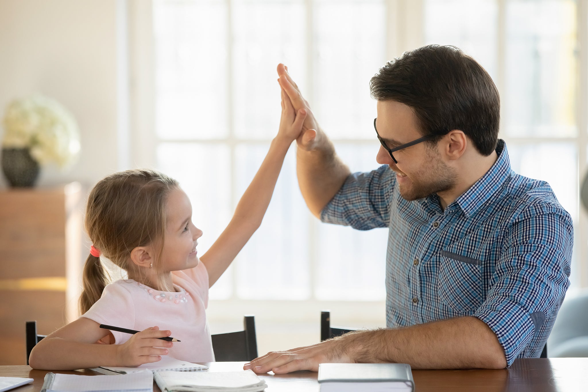 Father and daughter high-fiving at the kitchen table
