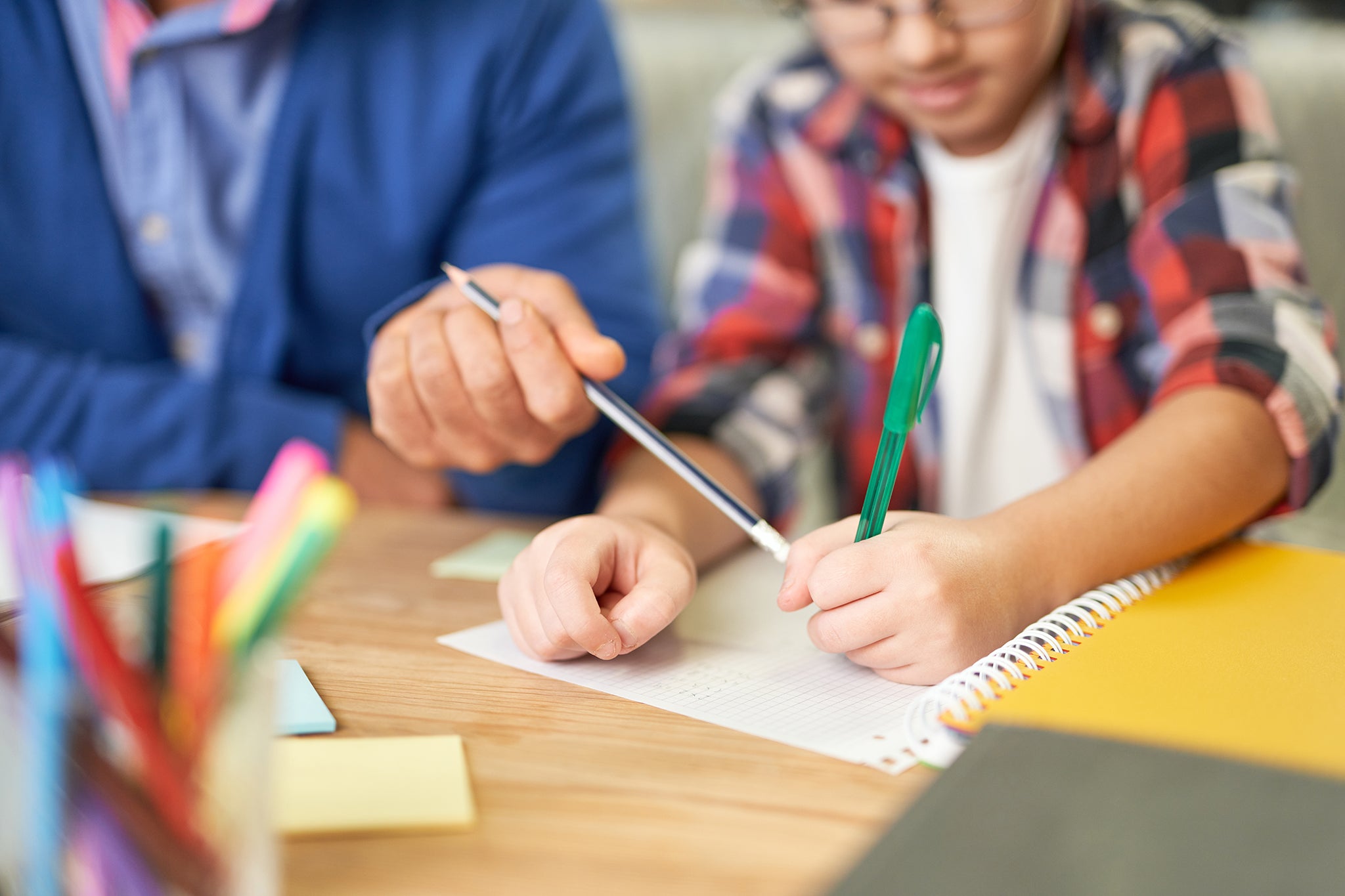 Close-up of a father and son writing on a piece of graph paper