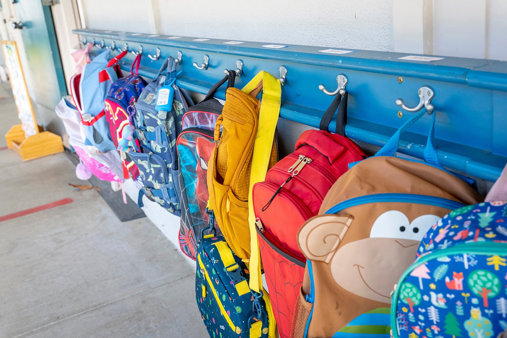 Row of children's backpacks hung on hooks at school