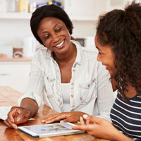 Black teen showing her mother her high school homework on an iPad