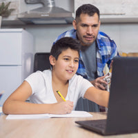 Hispanic father looking over middle school-age son's shoulder at homework on a laptop
